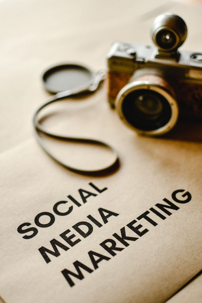 home-services-004 Close-up of a vintage camera on brown paper labeled with Social Media Marketing.